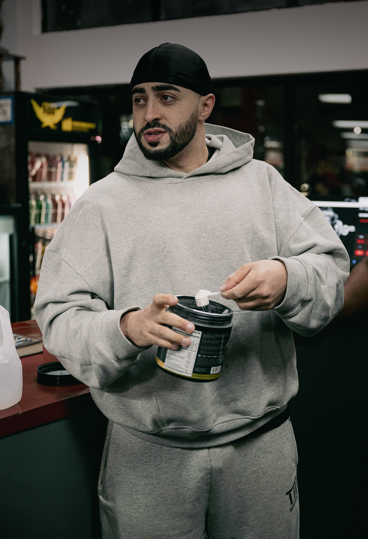 Haddy Abdelhady scooping KAGED supplement from a tub in a gym